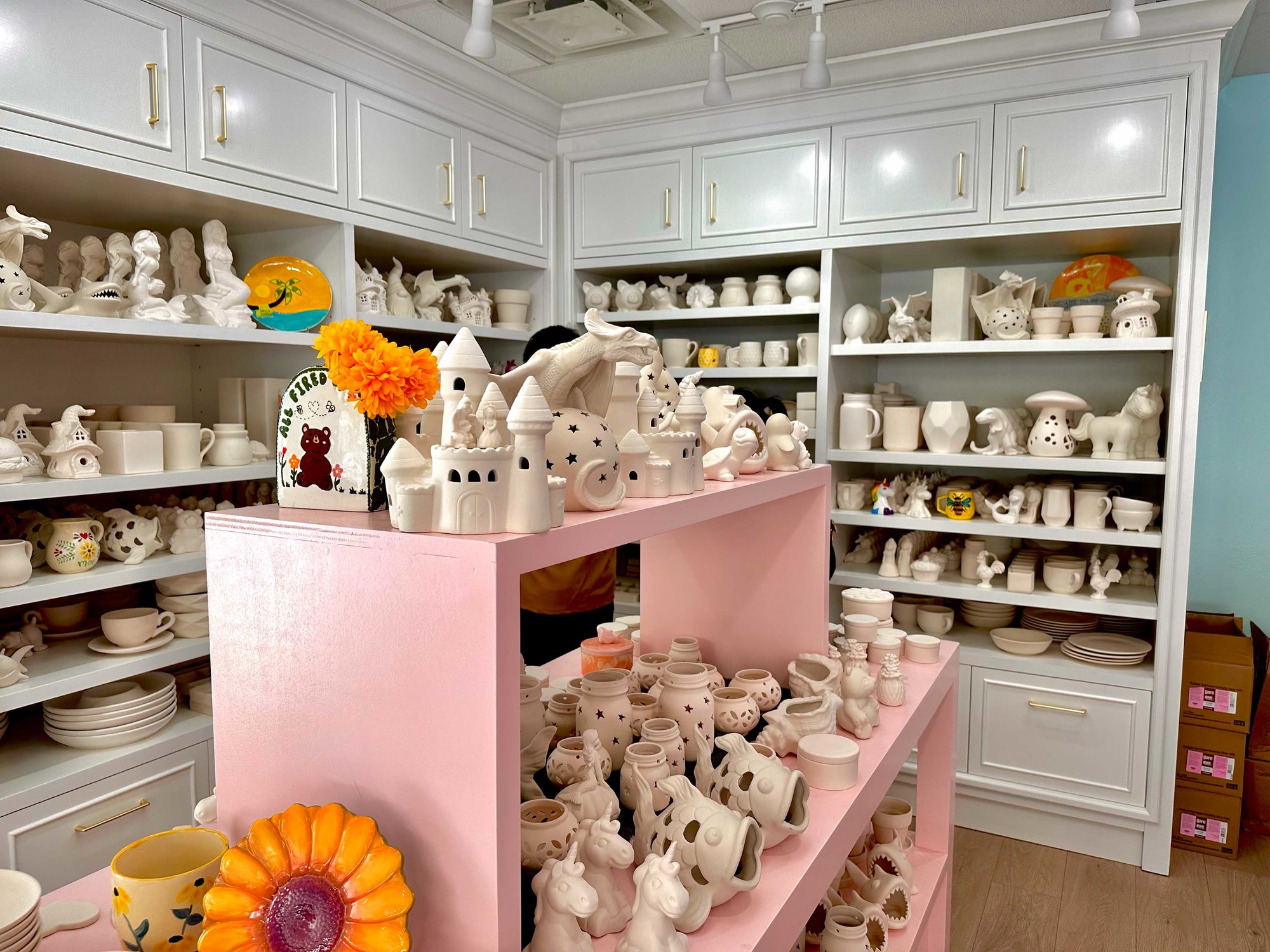 pink and white shelves of white clay pieces to paint